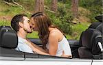 Young couple smooching on the backseat of a convertible