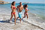 Cheerful friends jogging on the beach together