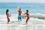 Cheerful friends playing with a beachball in the sea together