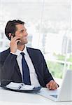 Cheerful businessman having a phone call in his office