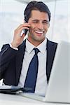 Smiling businessman having a phone call in his office