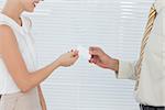 Businesswoman giving her business card to colleague in bright office