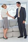 Cheerful business people shaking hands in bright office