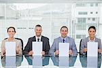 Smiling interview panel in bright office holding white paper sheets