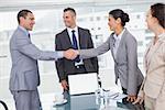 Cheerful business people meeting and shaking hands in bright office