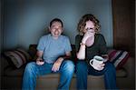 couple watching television laughing and embarrassed