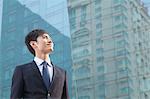 Young Businessman Looking Up, Glass Building,  Portrait