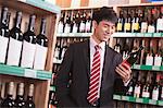 Young Man Choosing Wine in a Liquor Store