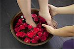 Woman's Feet Soaking in Water with Rose Petals