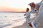 Two older people practicing Taijiquan on the beach at sunset, close up on hands