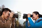 Young couple looking at each other through binoculars