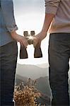 Young couple holding binoculars and looking at the sun