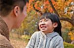 Father and daughter looking at each other in the park, autumn