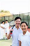 Young girl playing tennis with her coach