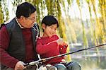 Grandfather and grandson putting lure on fishing line