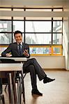 Businessman checking cell phone in company cafeteria