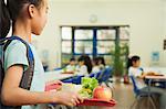 School girl holding food tray in school cafeteria