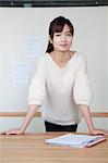 Young businesswoman standing with her hands on the table, portrait