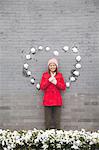 Young woman standing on wall with heart shaped snow balls