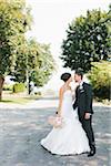 Portrait of Bride an Groom standing on street embracing and looking at each other