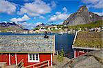 Red fishing rorbu huts by the fjord in town of Reine on Lofoten islands in Norway during summer