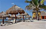 Beach on the seashore with umbrellas from straw, tents and plank beds for suntan