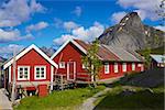 Red fishing rorbu huts by the fjord in town of Reine on Lofoten islands in Norway