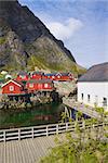 Typical red rorbu fishing huts on Lofoten islands in Norway reflecting in fjord