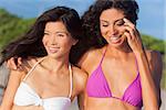 Two beautiful young women one Chinese Asian the other mixed race Hispanic in bikinis having fun at the beach