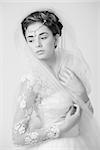 Black and white portrait of a beautiful seductive bride posing in white wedding dress with veil. Studio shot.