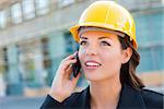 Young Professional Female Contractor Wearing Hard Hat at Contruction Site Using Cell Phone.
