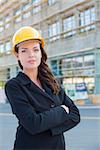 Portrait of Young Attractive Professional Female Contractor Wearing Hard Hat at Construction Site.