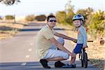 smiling cute boy with a balance bike spending fun time together with his handsome father