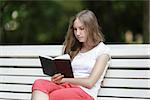 young girl reading book, sitting on the bench