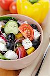 fresh greek salad in clay bowl, on wood table