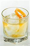 whiskey served on ice garnished with an orange twist isolated on a white background