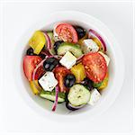 fresh greek salad in white bowl, isolated on white