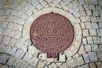 Budapest rusted sewer cap surrounded by pavement granite stones