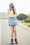 Beautiful stylish photographer taking a picture standing on a higway