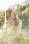 Blonde hipster girl sitting on the grass in summertime