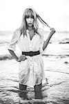 Sexy model with fringe standing in the sea staring at camera in artistic black and white shot