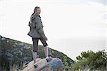 Rear view of woman standing on stone looking back smiling at camera