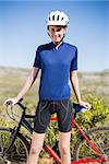 Woman holding and standing in front of bike looking at camera in the countryside