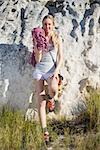 Smiling woman with climbing equipment leaning on rock