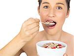 Smiling healthy model eating cereals on white background