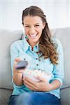 Happy woman watching television eating popcorn