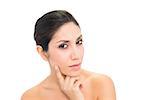 Thoughtful brunette with finger on her face looking at camera on white background