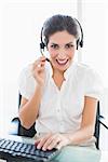 Smiling call centre agent working at her desk on a call in her office