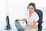 Happy call centre agent working on computer while on a call in her workplace