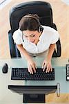 Pretty call center agent typing while on a call in her workplace